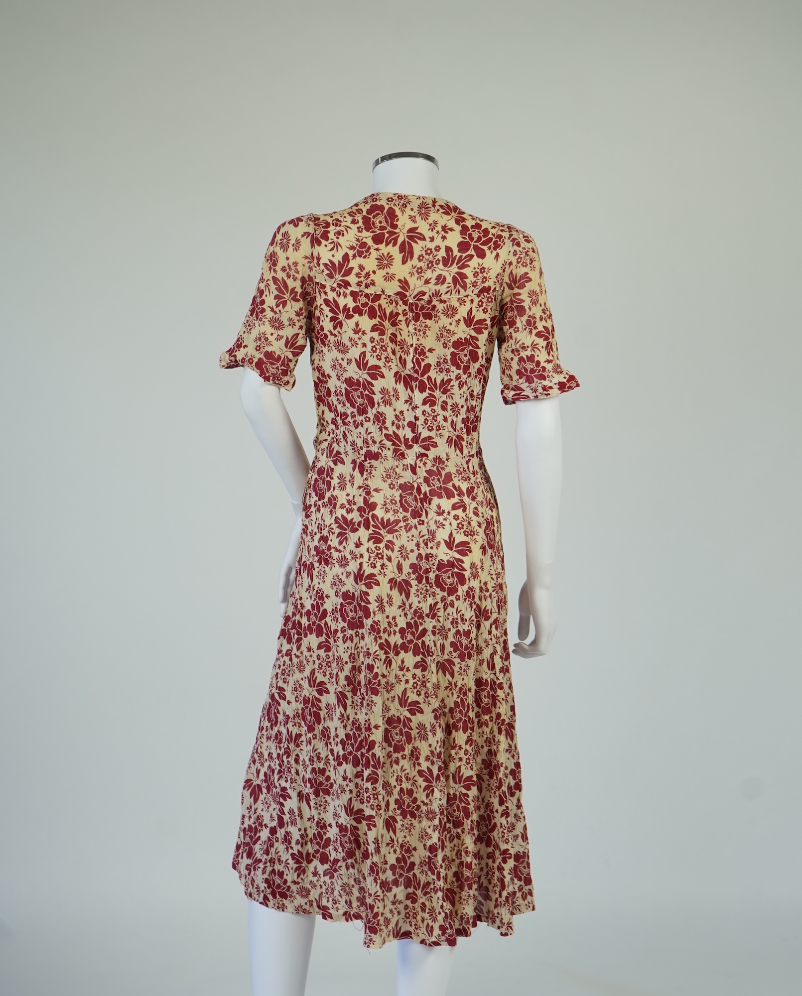 Two 1930's printed silk crepe summer day dresses together with a similar pale blue and black stripped summer day dress., Condition - the maroon and cream dress has damage to one sleeve, the green dress has worn under the